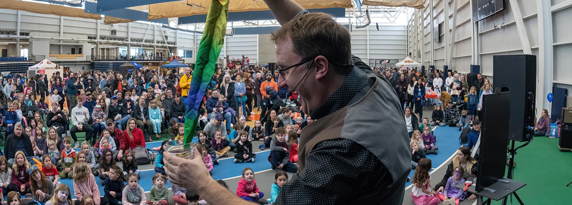 Magician performs on a stage in front of a large crowd