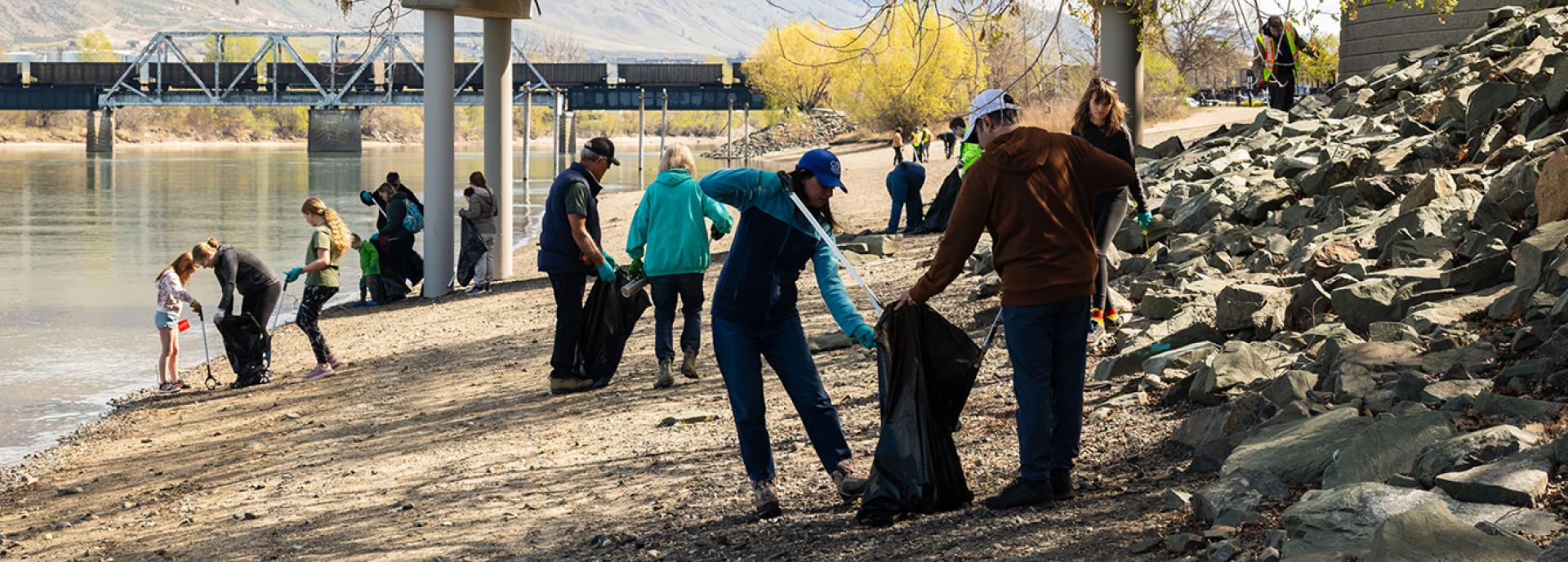group of people on a beach picking up garbage