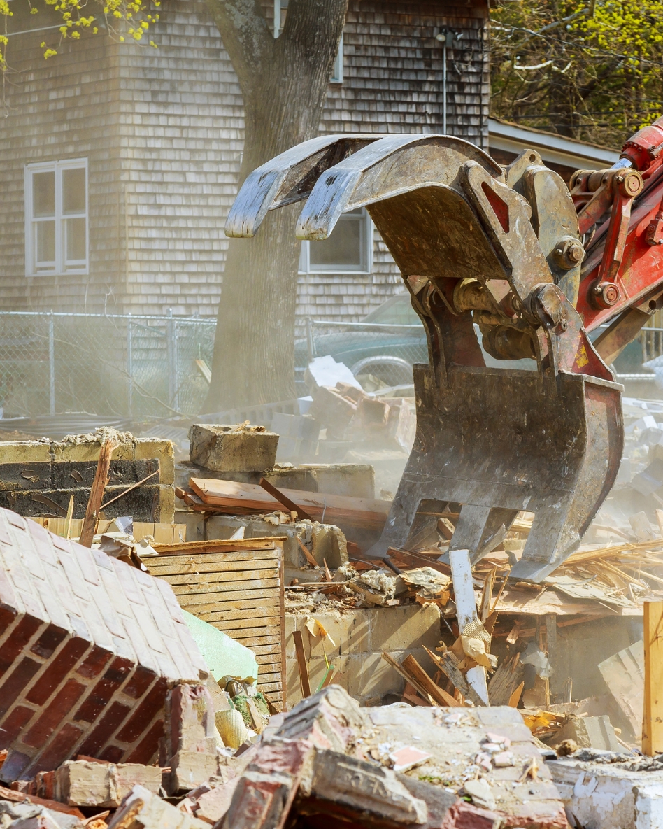 Heavy machinery demolishing a dwelling.