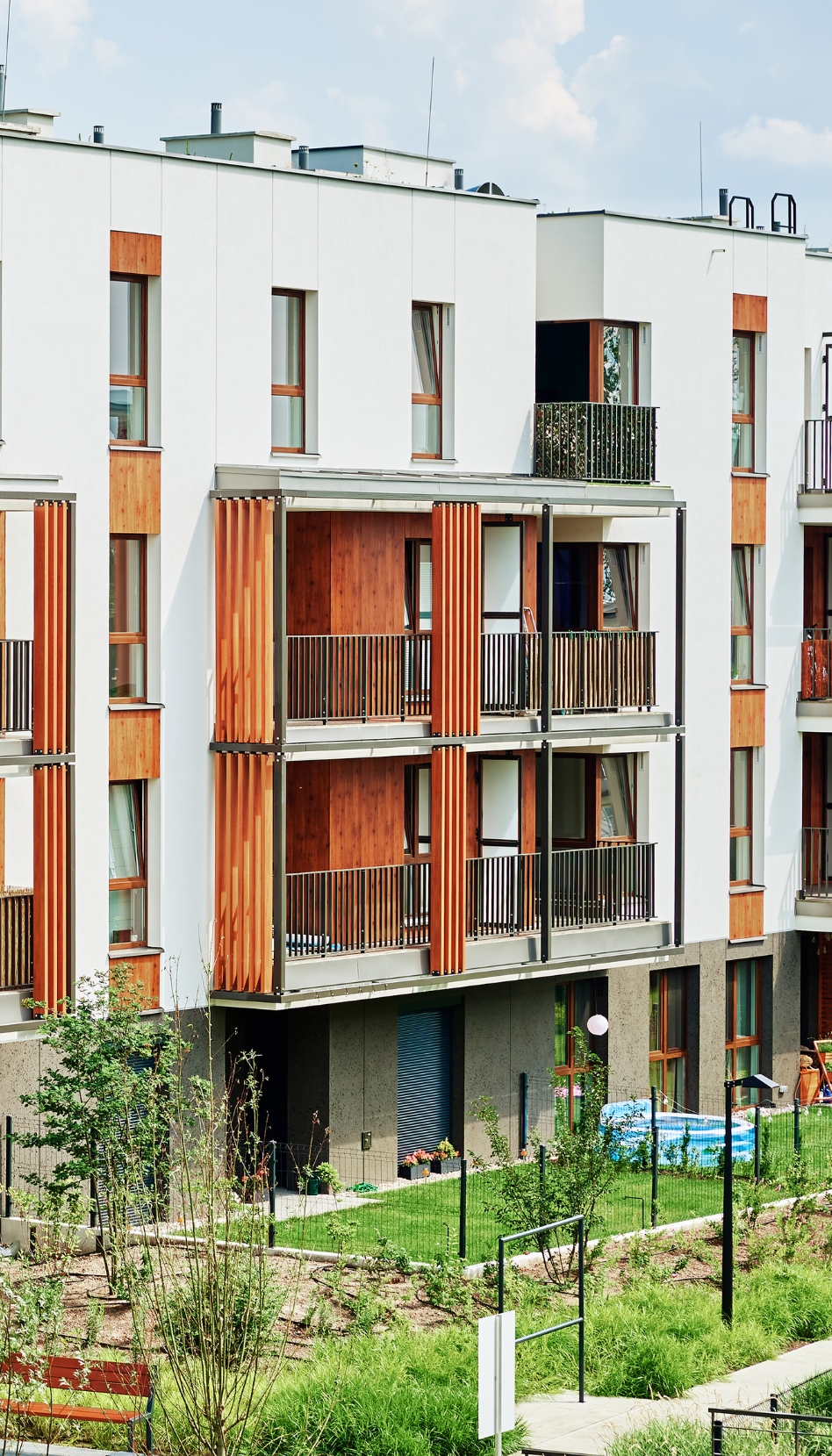 Street view of a white and wood panelled four-storey multi unit residential building.