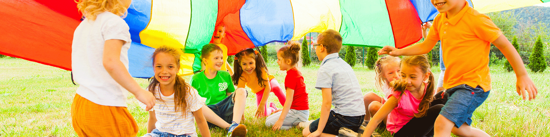 Kids playing under rainbow parachute